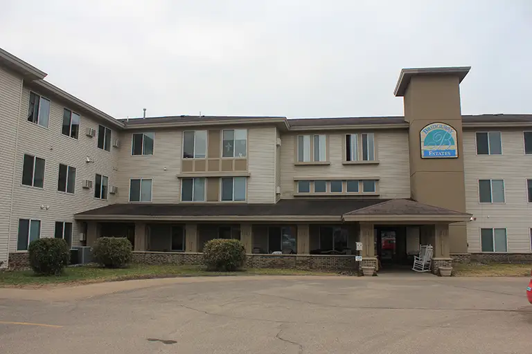 Three-story beige hotel building with multiple windows, a covered entrance, and the “AmericInn” sign visible on a tower section at the front, conveniently located near Bridgeway Estates. Three-story beige hotel building with multiple windows, a covered entrance, and the "AmericInn" sign visible on a tower section at the front, conveniently located near Bridgeway Estates.
