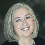 Smiling woman with shoulder-length gray hair, wearing a dark top and necklace, posed in front of a blurred dark background, representing St. Francis Health Services’ Outpatient Therapy in Minnesota. Smiling woman with shoulder-length gray hair, wearing a dark top and necklace, posed in front of a blurred dark background, representing St. Francis Health Services' Outpatient Therapy in Minnesota.